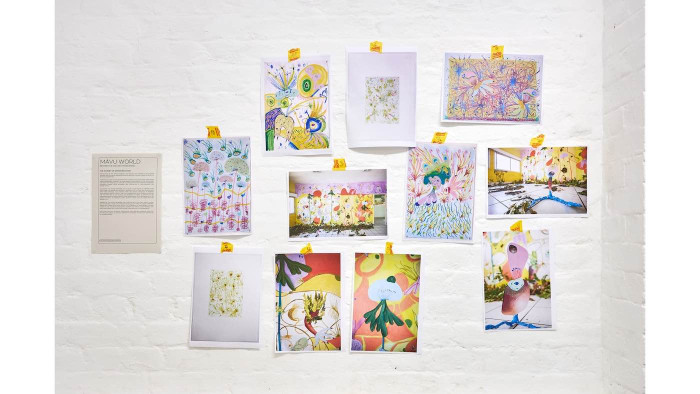 Artworks taped to a white wall. 