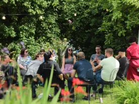 People talking in a circle in a garden setting. 
