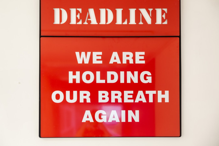 A bright red sign reads 'Deadline: We are holding out breath'.