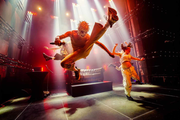 Three people on stage jumping. 