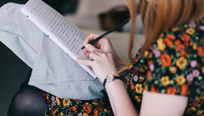 View from behind of a person writing in a notebook. 