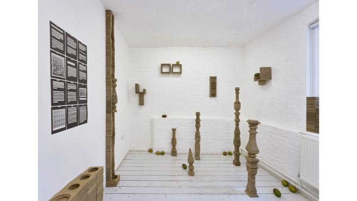 A gallery space with works on the walls and sculptural pieces in the middle. 
