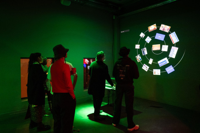 People in a green-lit room engaging with an installation. 