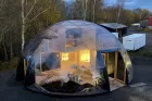 A minimalist wooden creation space inside a small, transparent geodesic dome.
