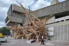 A wooden installation outside an industrial-type cement building. 