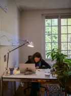 A person working at their desk with a window behind them. 