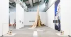 An exhibition space with tent-like shape and art on the walls. 