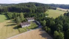 A large house surrounded by woods and fields. 
