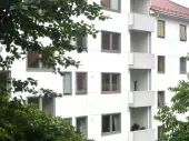 A multi-story white building with some trees. 