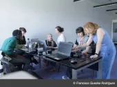 People around a table looking at computers and talking. 