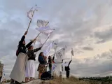 People standing on a raised space holding home-made flags aloft. 