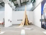 An exhibition space with tent-like shape and art on the walls. 