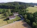 A large house surrounded by woods and fields. 