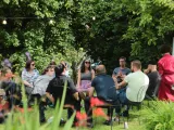 People talking in a circle in a garden setting. 
