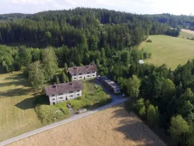A large house surrounded by woods and fields. 
